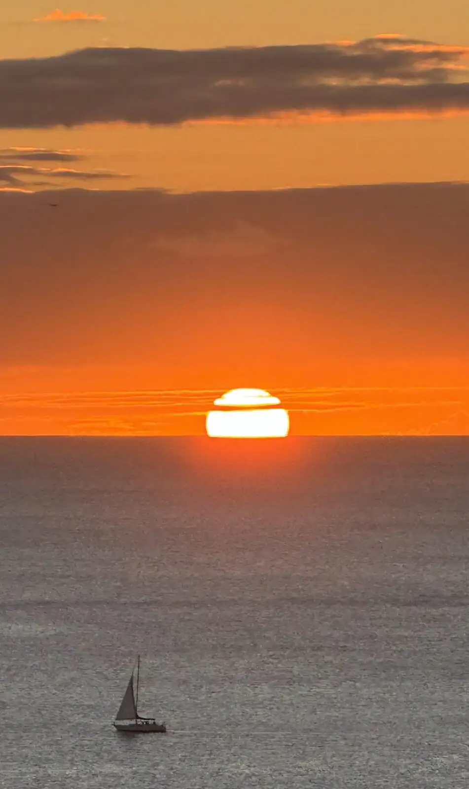 Sunset over the ocean with a sailboat